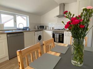 una cocina con una mesa con flores en un jarrón en Islas Cottage, a home in the Heart of Speyside, en Dufftown
