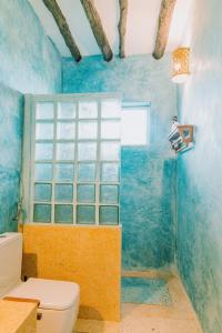a blue bathroom with a toilet and a window at Mkunguni Villas in Bwejuu