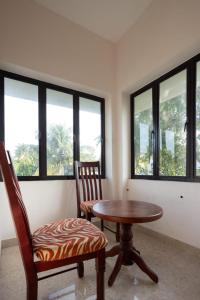 Habitación con mesa, 2 sillas y ventanas. en Homested Homestay Fort Kochi en Kochi
