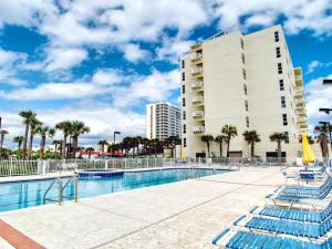 a swimming pool with blue chairs in front of a building at Sans Souci #605 in Pensacola Beach