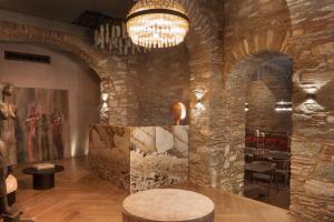 - un hall avec un grand mur en pierre et un lustre dans l'établissement Castro Hotel Syros, à Ermoúpoli