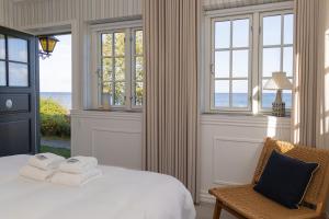 a bedroom with a bed and a chair and windows at Allinge Badehotel in Allinge