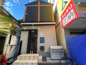una pequeña casa con un cartel delante en SAMURAI STAY 黄金町-Male Only, en Nishi-hiranumachō