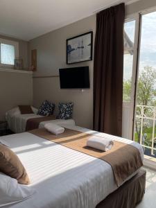 een slaapkamer met 2 bedden, een tv en een raam bij Logis Hôtel- Restaurant Le Relais Guillaume de Normandy in Saint-Valery-sur-Somme