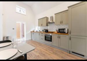 a kitchen with white cabinets and a wooden floor at The Dairy - Contemporary 1 bedroom cottage 