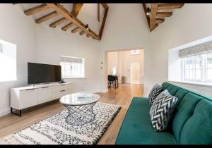 uma sala de estar com um sofá verde e uma televisão em The Dairy - Contemporary 1 bedroom cottage 