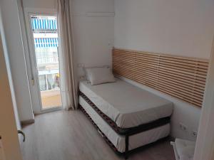um pequeno quarto com uma cama e uma janela em Luxury Apartment Accommodation, next to beach & train station Calella em Calella
