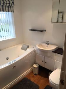 a bathroom with a tub and a sink and a toilet at Luxury Tranquil Cottage with Hot tub, Log burner and Jacuzzi Bath in Alford