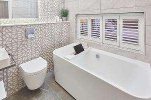 a bathroom with a white tub and a toilet and a sink at Host & Stay - The Stables in Yarm +12 photos