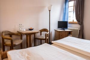 um quarto com duas camas e uma mesa e uma televisão em Marktplatzhotel - Restaurant Tafelspitz em Weinheim