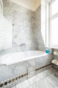 baño blanco con bañera y ventana en Pension Primavera, en Viena