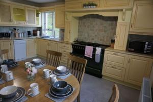 uma cozinha com uma mesa de madeira com cadeiras e electrodomésticos em Rarooey House em Donegal