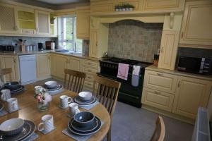 una cucina con tavolo in legno, sedie ed elettrodomestici di Rarooey House a Donegal
