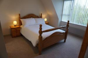 sypialnia z drewnianym łóżkiem z 2 stolikami nocnymi i oknem w obiekcie Rarooey House w mieście Donegal