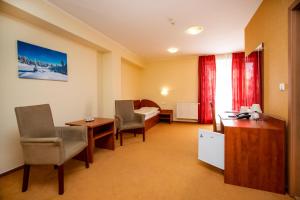 una camera d'albergo con letto, scrivania e sedie di Hotel Boss a Žilina