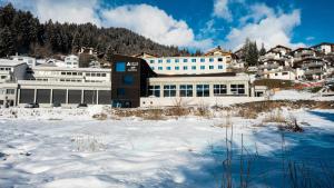 a building in the snow in front of a mountain at wellnessHostel3000 in Laax