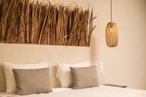 Atma Beach Rooms & Suites في فاليراكي: غرفة نوم بسرير ومخدات وقلادة خفيفة