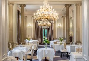 un comedor con mesas blancas y una lámpara de araña en Château des Reynats en Chancelade