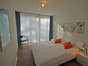 ein Schlafzimmer mit einem großen weißen Bett mit orangefarbenen Kissen in der Unterkunft Ferienwohnung "Albrecht der Seebär" in Kühlungsborn