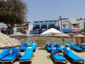 eine Gruppe blauer Stühle und Sonnenschirme am Strand in der Unterkunft Queen Victoria Suit Apart OTEL in Bodrum City