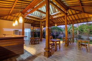 - un grand pavillon en bois avec des tables et des chaises dans l'établissement Pondooks Joglo, à Nusa Lembongan