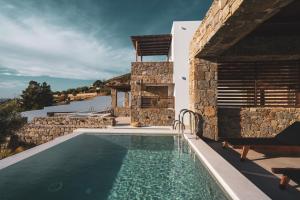 eine Villa mit einem Pool und einem Haus in der Unterkunft Kouros Blanc Resort & Suites in Pounda
