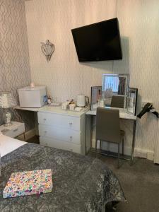 a bedroom with a bed and a desk and a tv at Sorrento House in Blackpool