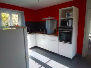 a kitchen with white cabinets and a red wall at Domaine de gentilly la maison 