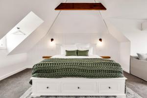 a bedroom with a white bed with a green blanket at Marleys Loft in Mudgee