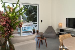 比雷埃夫斯的住宿－La Mer Apartment by LobbySquare，客厅配有沙发和鲜花桌