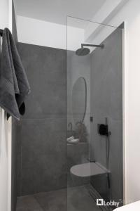 a bathroom with a glass shower with a sink at La Mer Apartment by LobbySquare in Piraeus