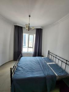 a bedroom with a bed with a blue comforter and a window at Furnished Studio apartment near Business Bay Metro Station in Dubai