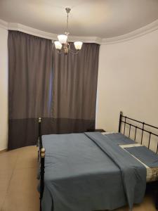 a bedroom with a bed with a blue blanket and a chandelier at Furnished Studio apartment near Business Bay Metro Station in Dubai