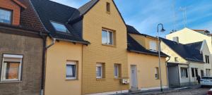 ein gelbes Haus mit schwarzem Dach auf einer Straße in der Unterkunft Zollzeche Stadtwohnungen in Staßfurt