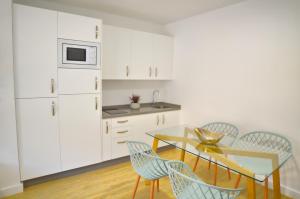 a kitchen with white cabinets and a table and chairs at Leo Canela in Isla Canela