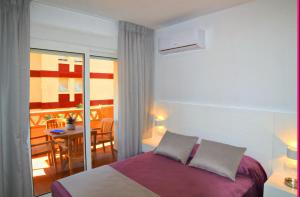 a bedroom with a bed and a balcony with a table at Leo Canela in Isla Canela