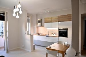 羅馬的住宿－Emerenziana Lovely Apartment，厨房配有白色橱柜和木桌