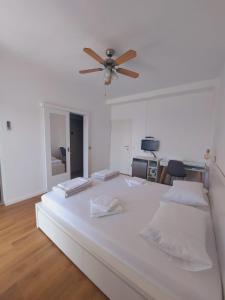 a bedroom with a large white bed with a ceiling fan at Vinko rooms in Primošten