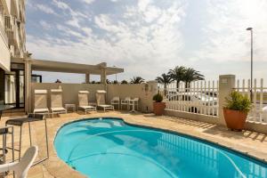 a swimming pool on a balcony with chairs and tables at Mouille Point Apartments in Cape Town