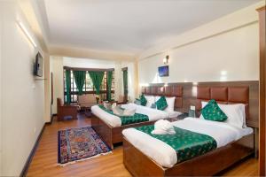Zimmer mit 3 Betten und grünen Kissen in der Unterkunft Muscatel BhumSang - 200 Mts from Mall Road in Darjeeling