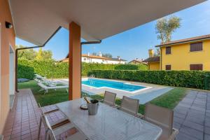 un patio con mesa y sillas junto a una piscina en Residence Albarella -Happy Rentals, en Isola Albarella