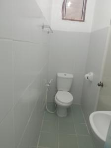 a white bathroom with a toilet and a sink at Bucana beachfront guesthouse in El Nido