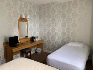 a room with two beds and a desk with a mirror at Waterford Lodge Hotel in Morpeth