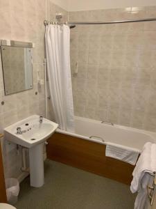 a bathroom with a sink and a bath tub with a shower at Waterford Lodge Hotel in Morpeth