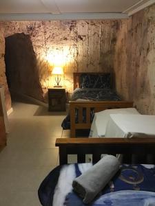 a room with two beds and a lamp on a wall at Pop’n’nin Dugout Accommodation at Coober Pedy Views in Coober Pedy
