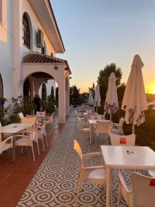 un restaurante con mesas y sombrillas en un patio en Hotel Meson Fuente del Pino, en Olvera