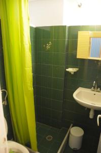 a bathroom with a green shower curtain and a sink at Chalikias Rooms in Asprogerakata