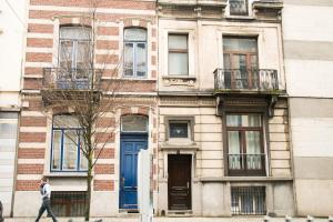 a man walking past a brick building with blue doors at Archimede Guest House in Brussels