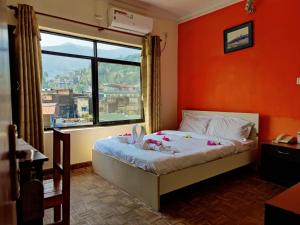 ein Schlafzimmer mit einem Bett mit einer orangefarbenen Wand und einem Fenster in der Unterkunft Gateway Himalaya Resort in Ghanpokhara
