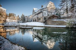 un bâtiment dans la neige à côté d'une rivière dans l'établissement Gut Hungenbach, à Kürten